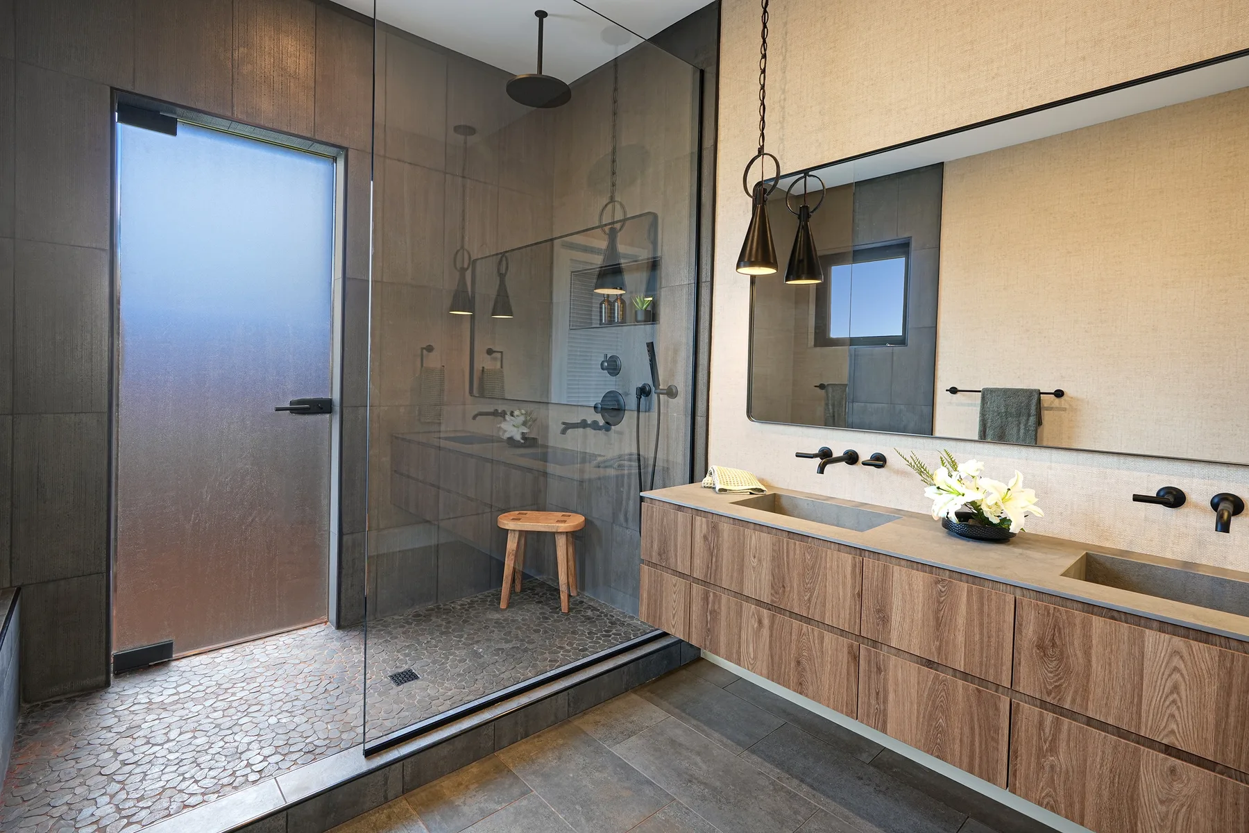 Un baño moderno con ducha de vidrio, tocador y un espejo grande.