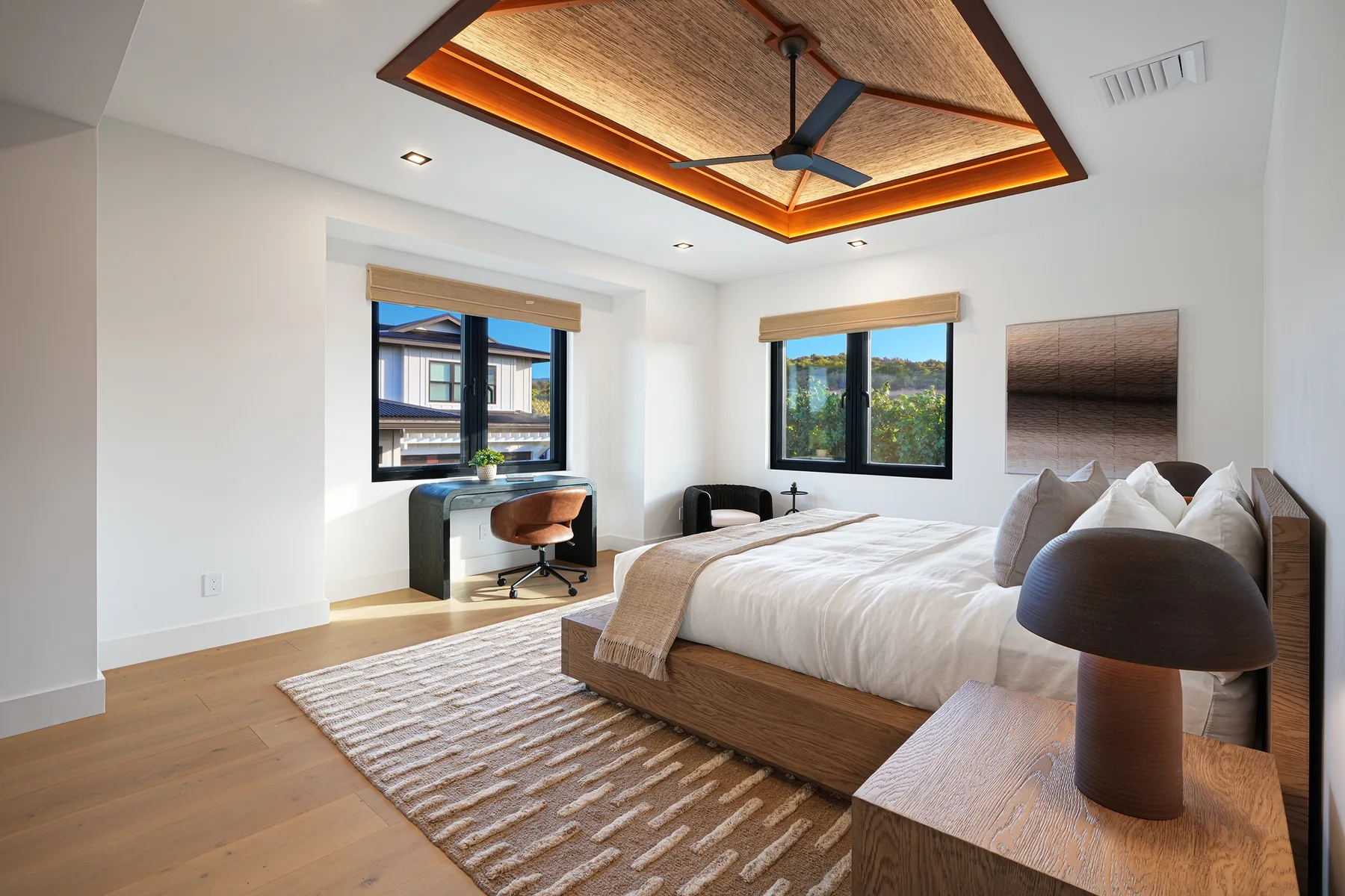 Un dormitorio luminoso con una cama grande y ventanas con vistas a la vegetación.