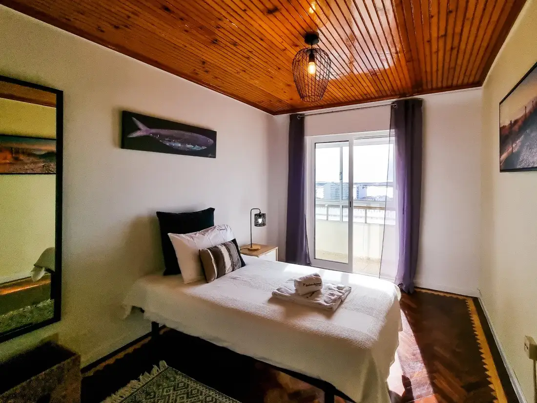 Un dormitorio con cama, mesa de noche y puertas corredizas de vidrio que dan a un balcón.