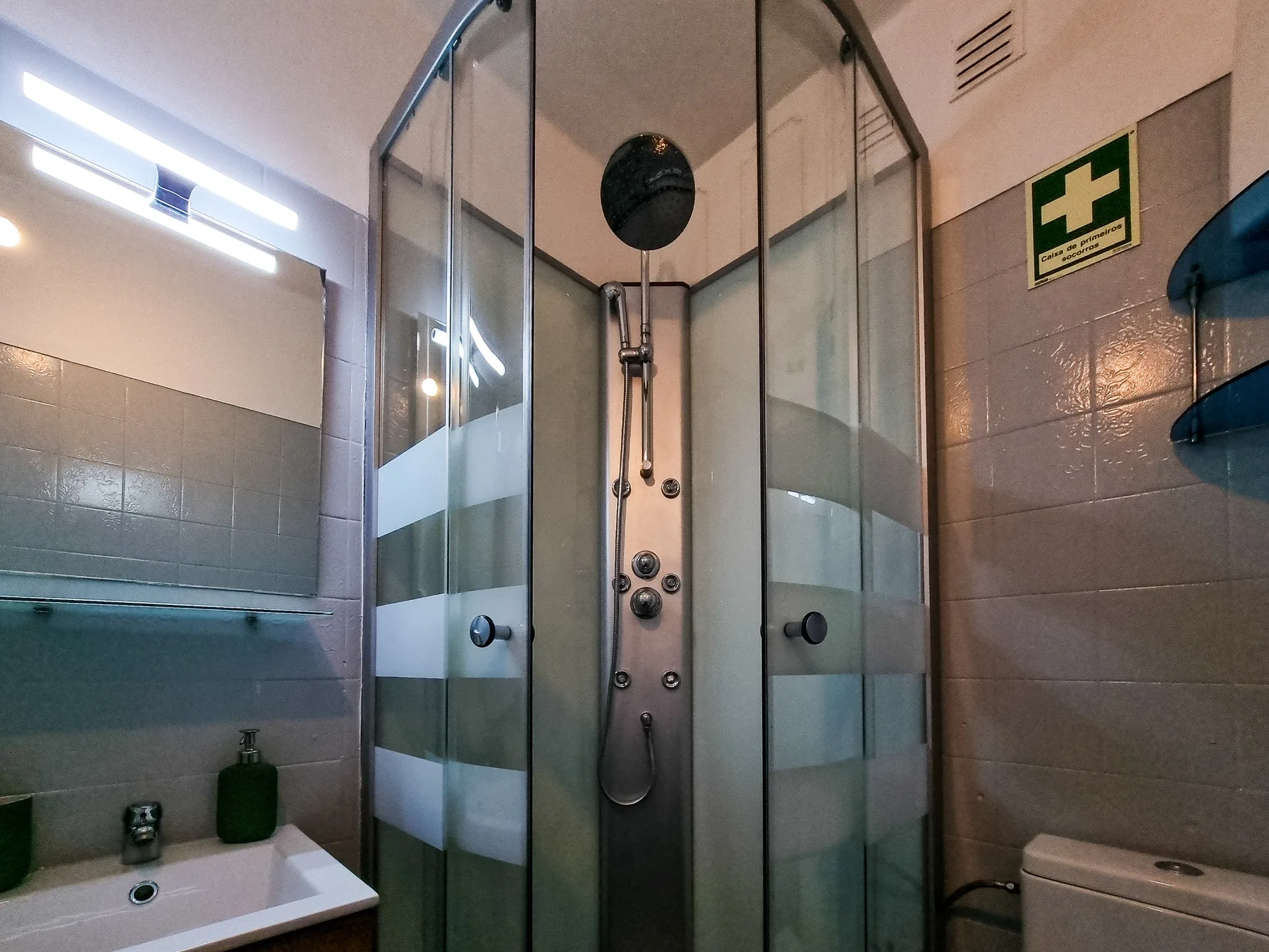 Un baño con azulejos, una ducha de vidrio y un lavabo.