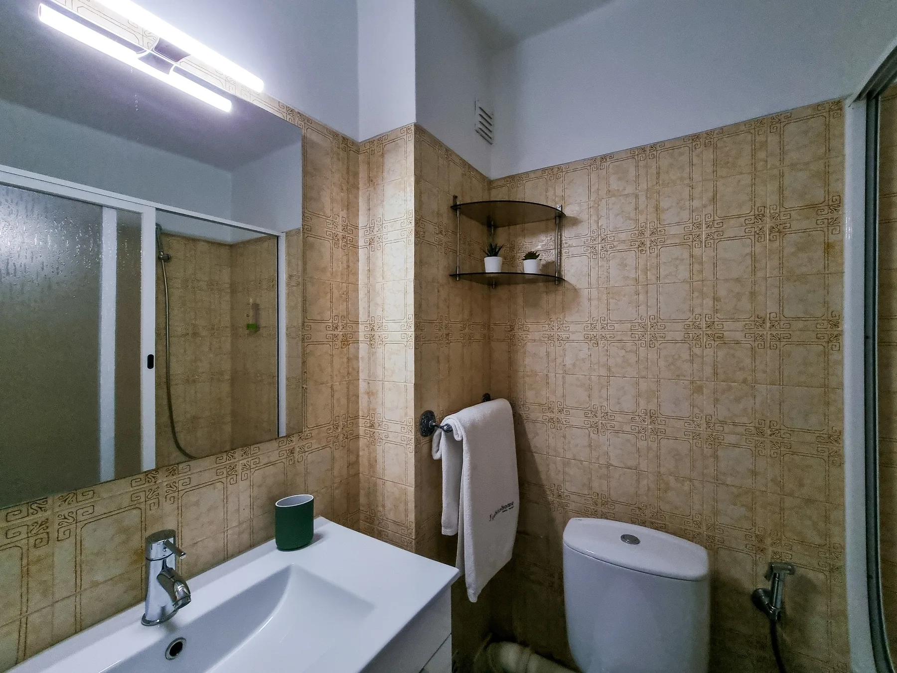 Un baño con azulejos, lavabo, espejo e inodoro.