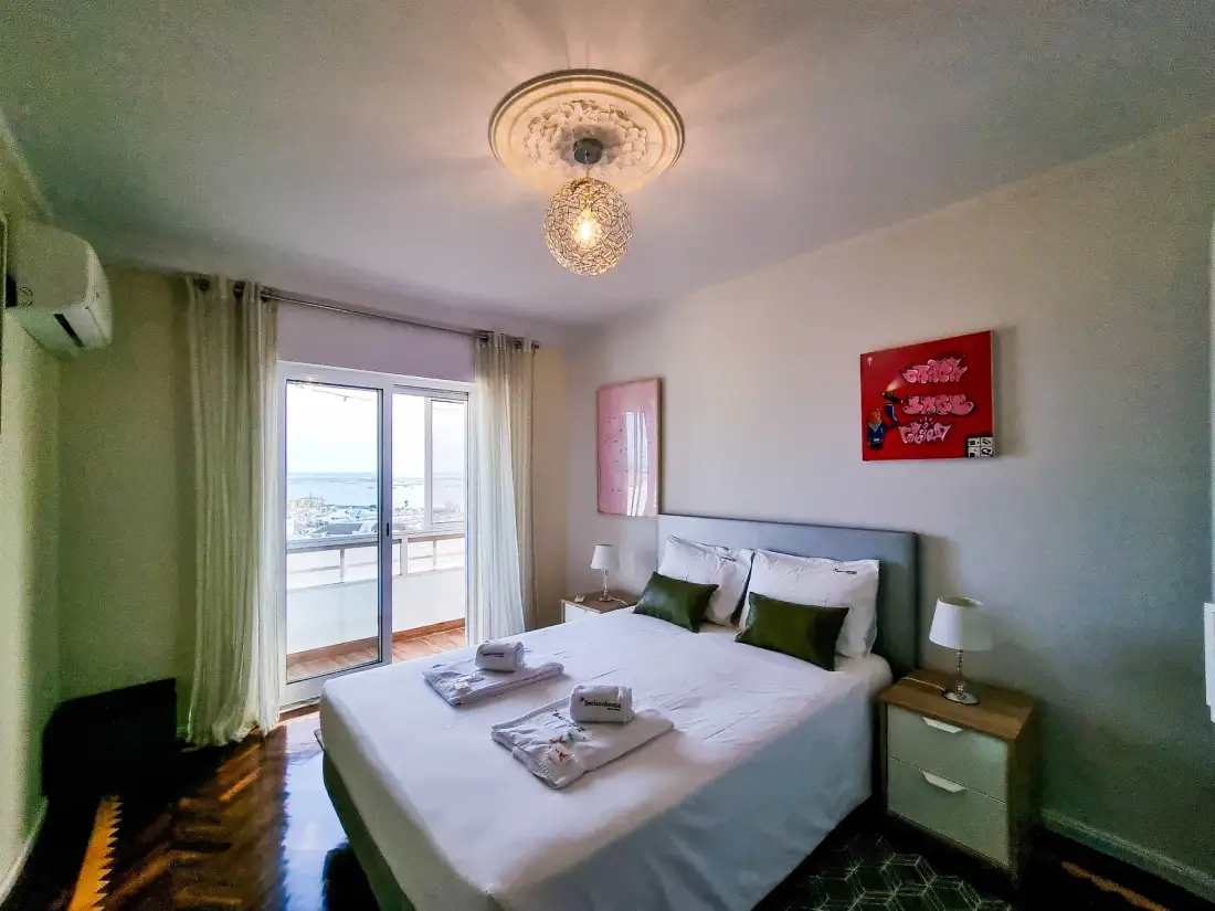 Un dormitorio con una cama junto a puertas acristaladas que dan a un balcón.