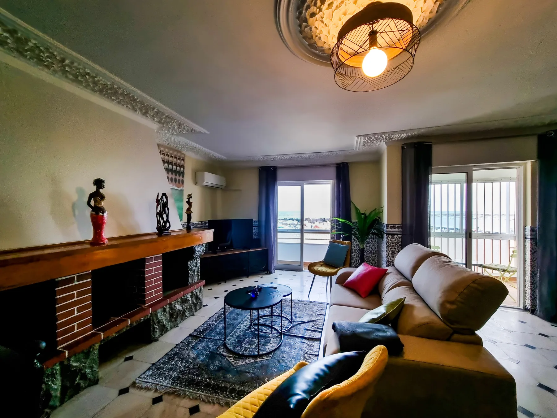 Una sala de estar con chimenea, asientos y puertas que dan a un balcón.