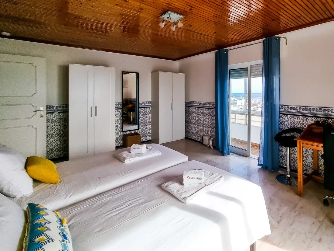 Un dormitorio con dos camas, armarios y una puerta al balcón.