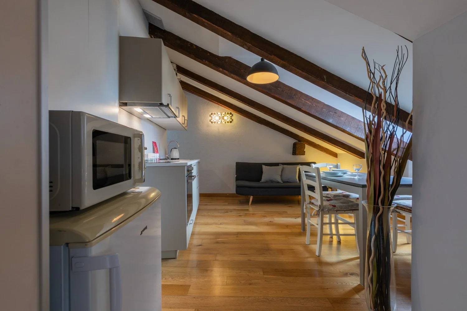 An attic kitchen and dining area with sloped ceilings and exposed beams.