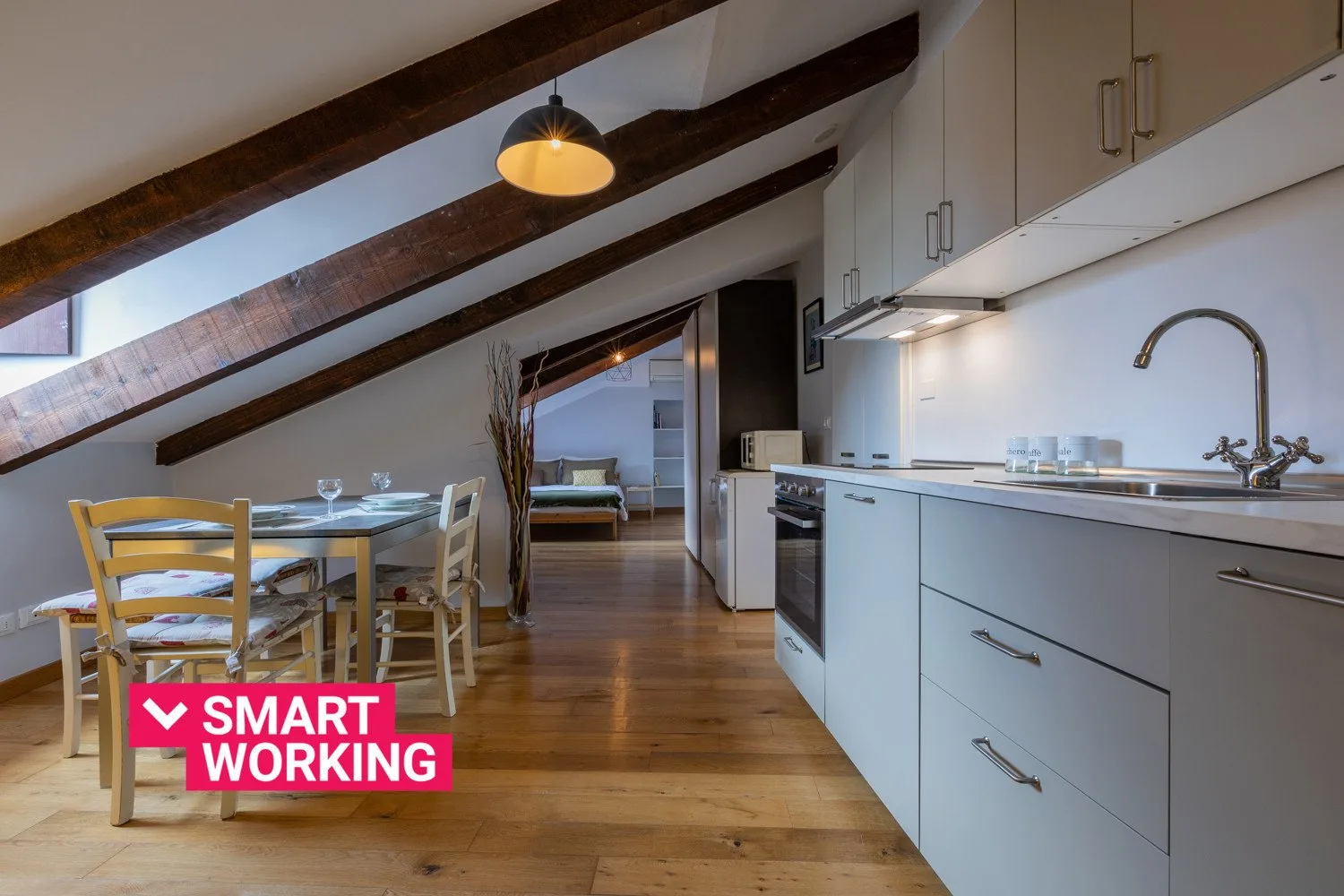 An open-plan kitchen and dining area with sloped ceilings and exposed beams.