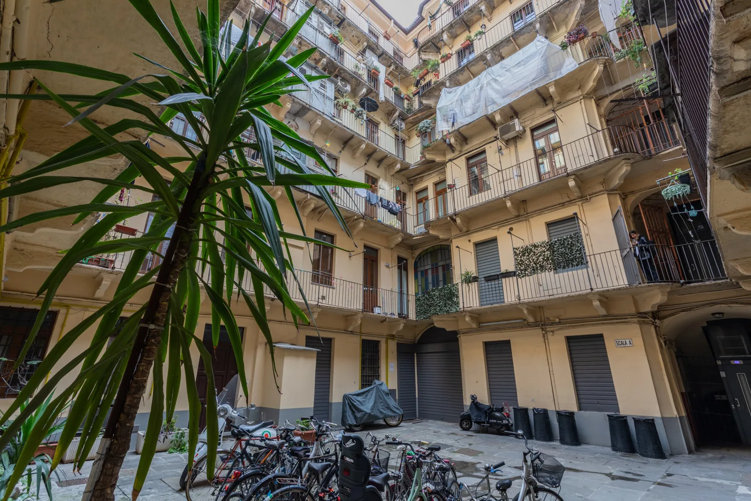 An apartment courtyard with balconies overlooking a paved area and parked bicycles.