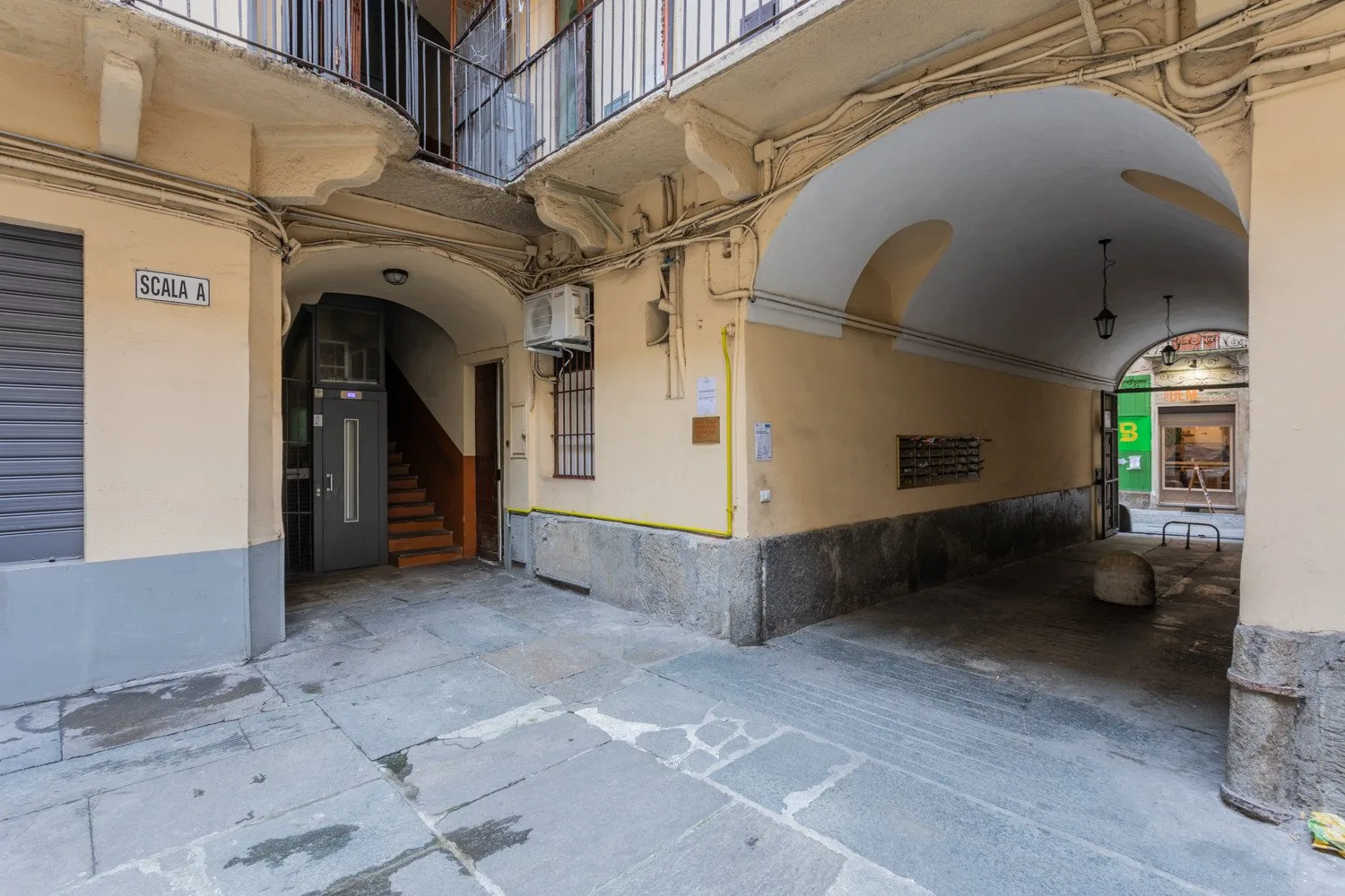 A covered courtyard passage with an arched opening and a stairway.