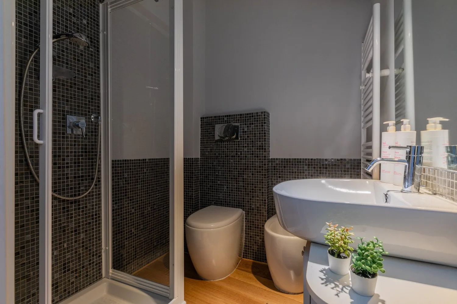A bathroom with a glass shower, toilet, and sink.