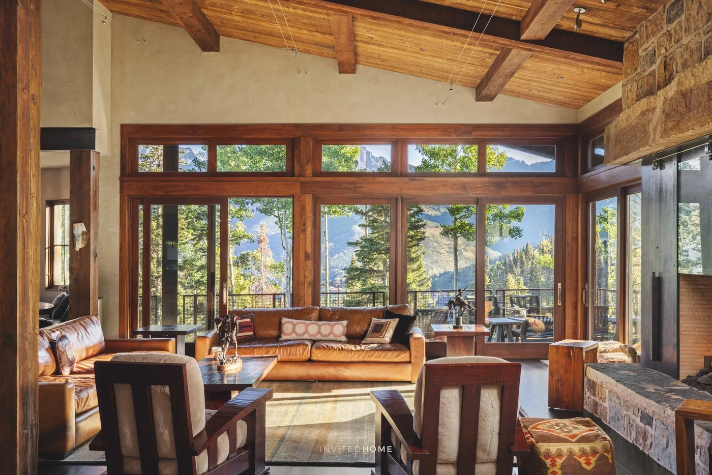 A bright living room with seating and large windows overlooking trees and mountains.
