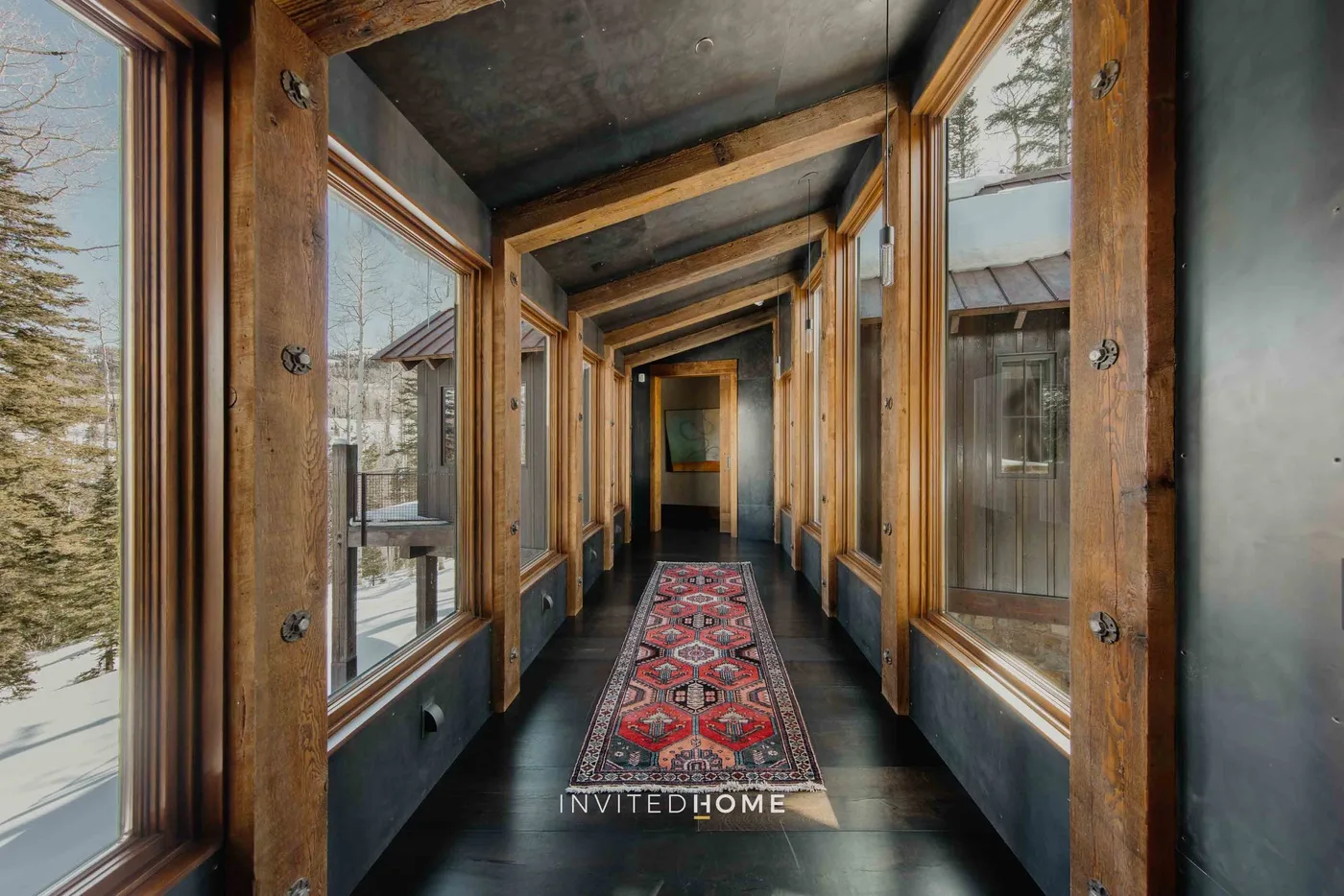 A long hallway with large windows and a patterned runner.