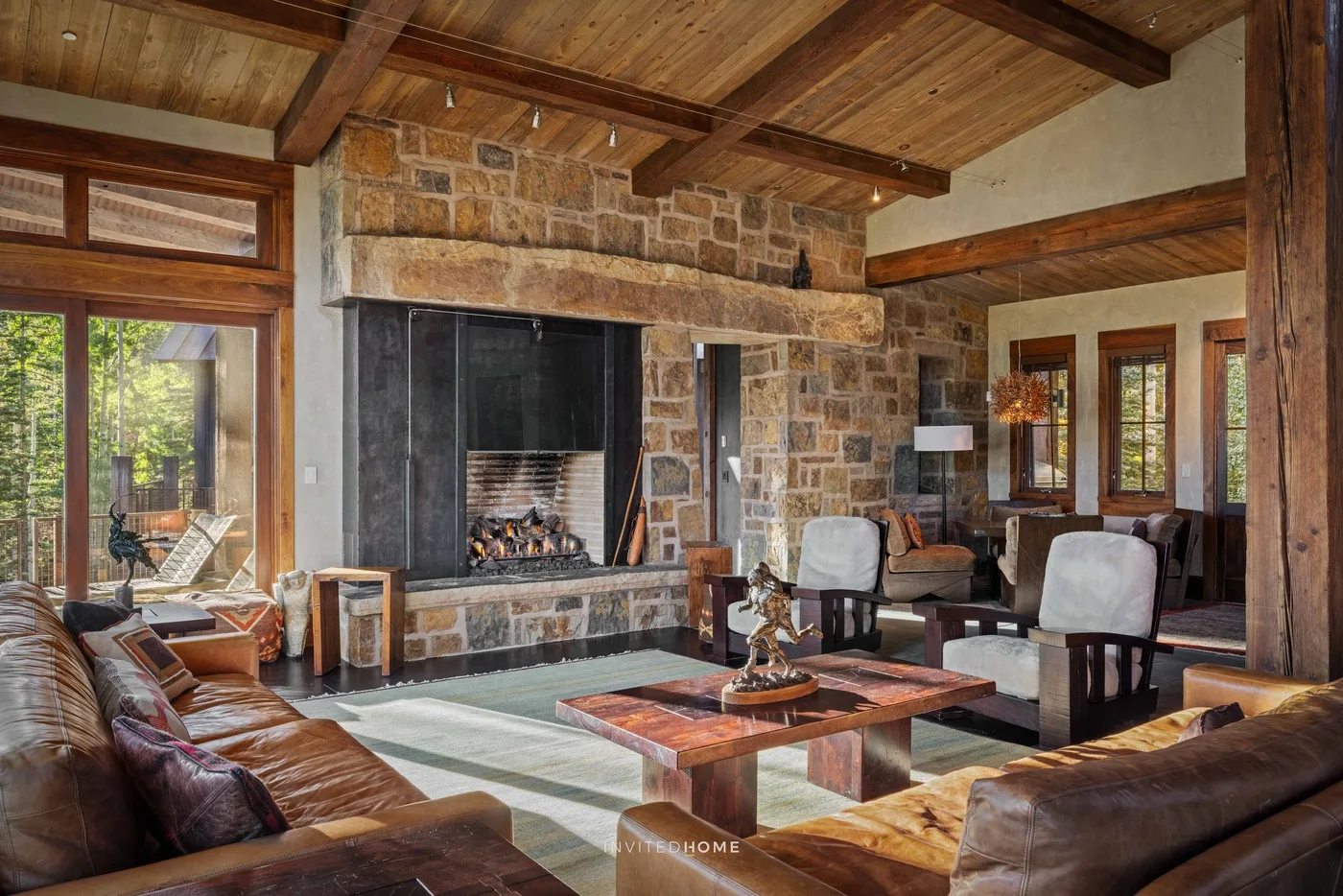 A spacious living room with a stone fireplace and seating around a low table.