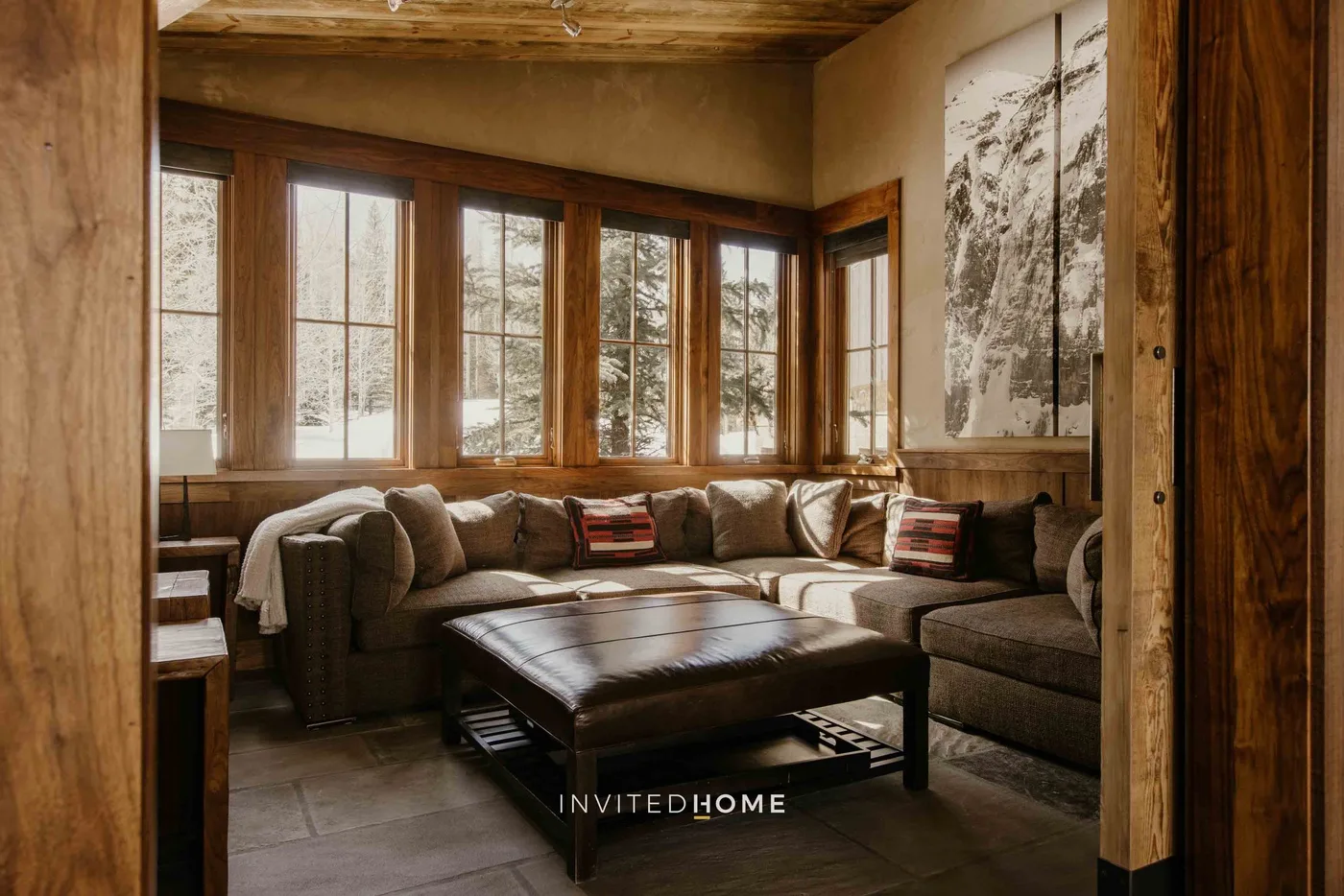 A living room with sectional seating and a low coffee table beside large windows.
