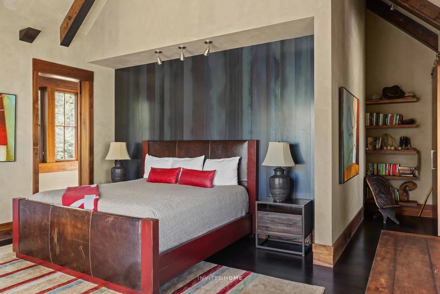 A bedroom with a large bed, bedside lamps, and a dark accent wall.