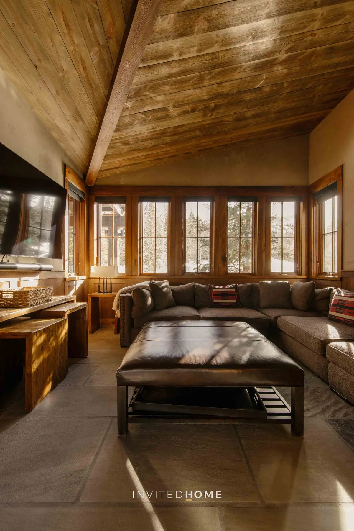 A living room with a sectional seating area, coffee table, and large windows.