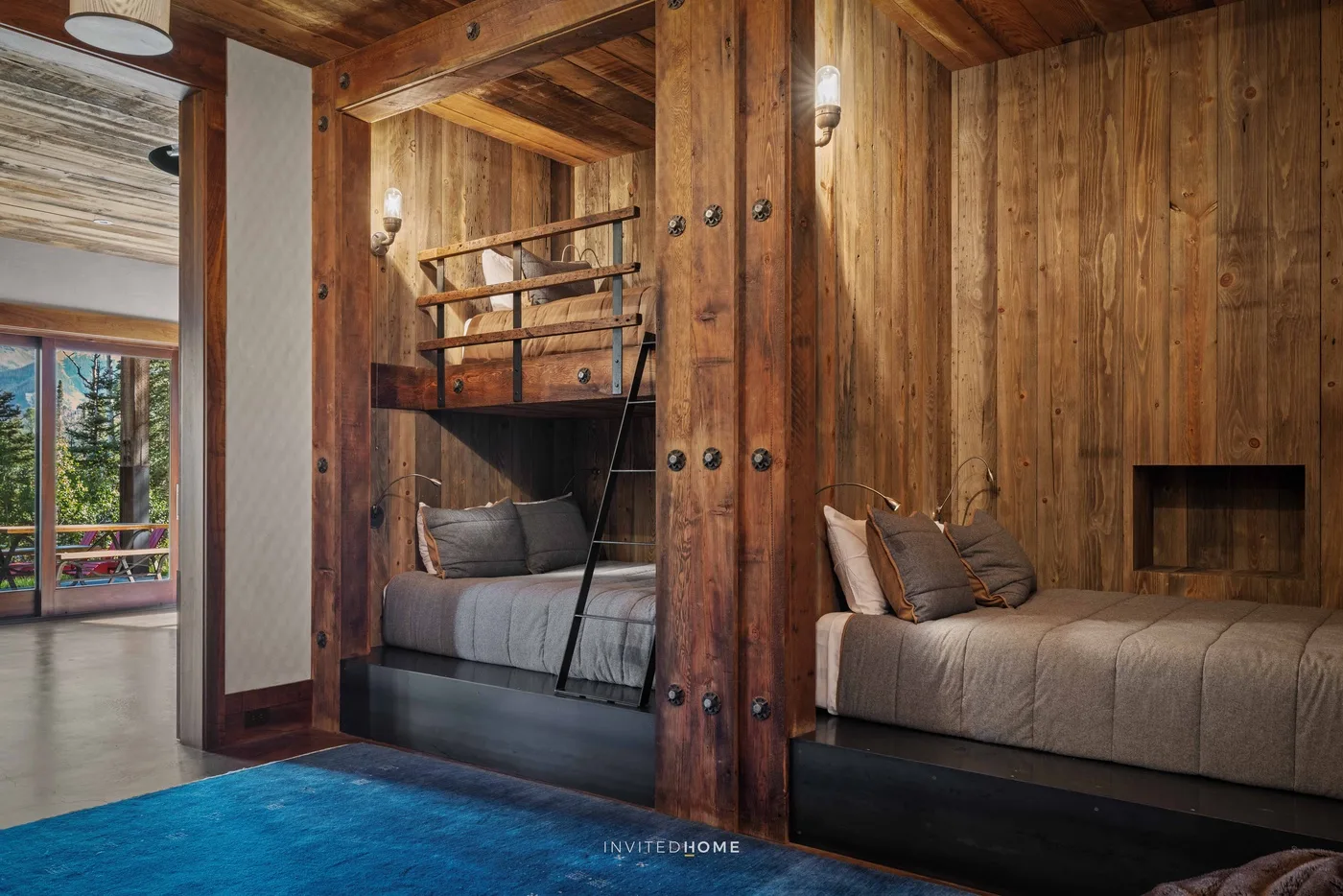 A wood-paneled bedroom with two built-in beds and a blue rug.