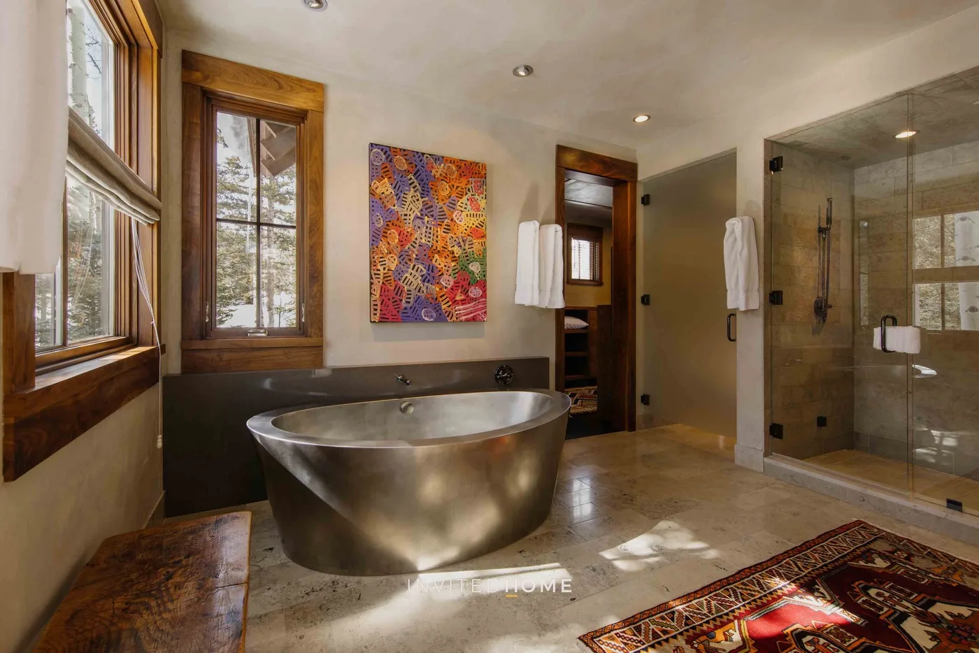 A bathroom with a freestanding bathtub, windows, and a glass shower.