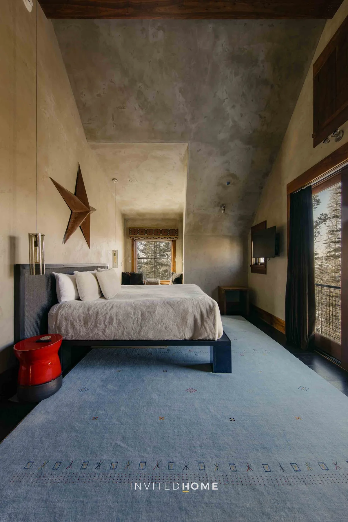 A bedroom with a raised bed, a star-shaped wall decoration, and a large window.