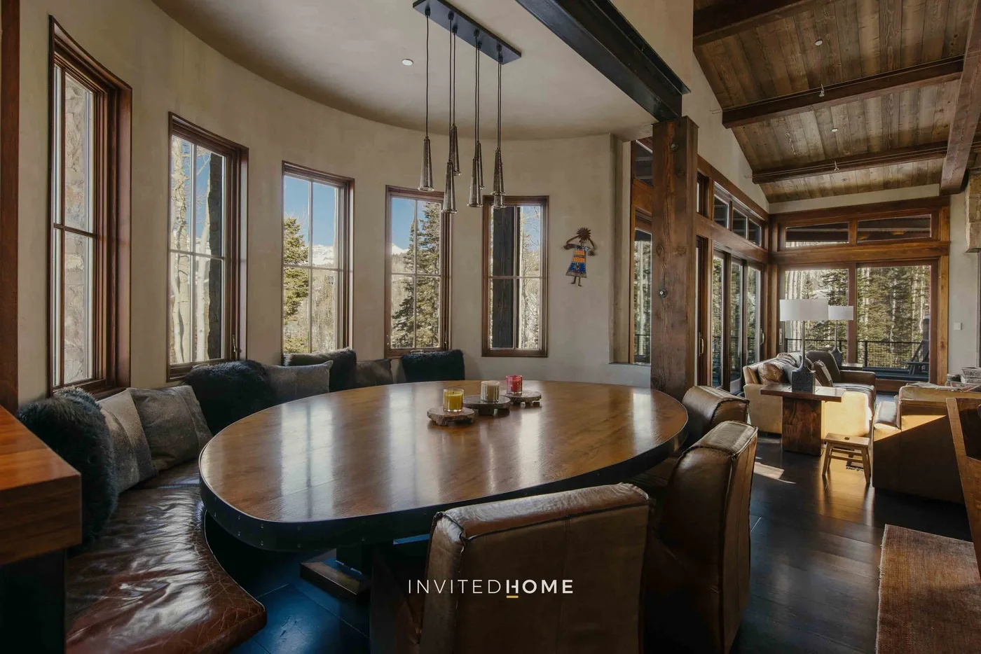 A dining area with a large oval table, seating, and tall windows.
