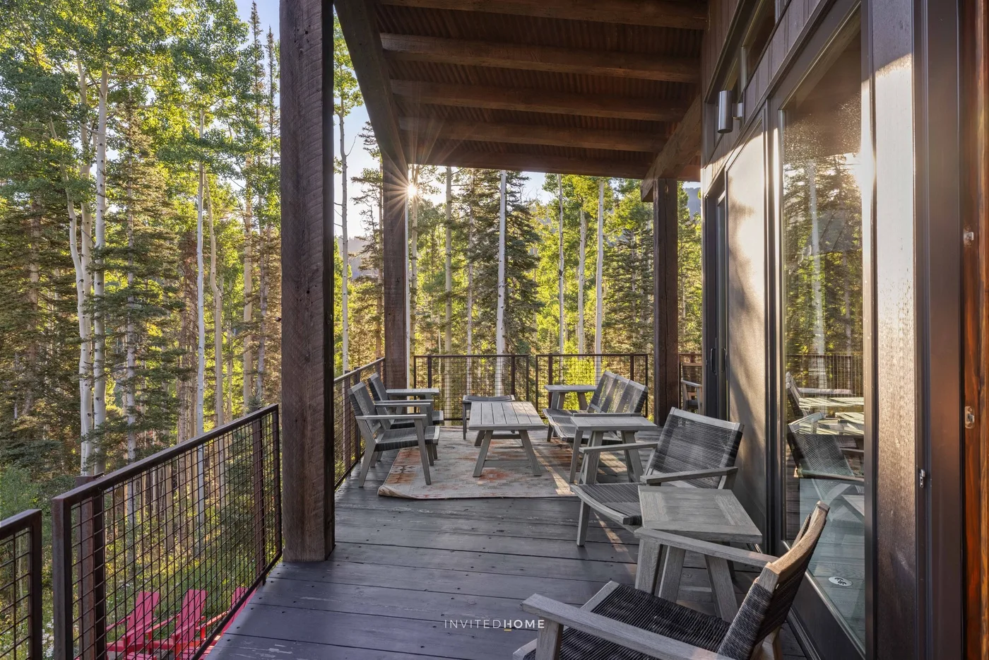 A covered deck with seating overlooks a wooded landscape.