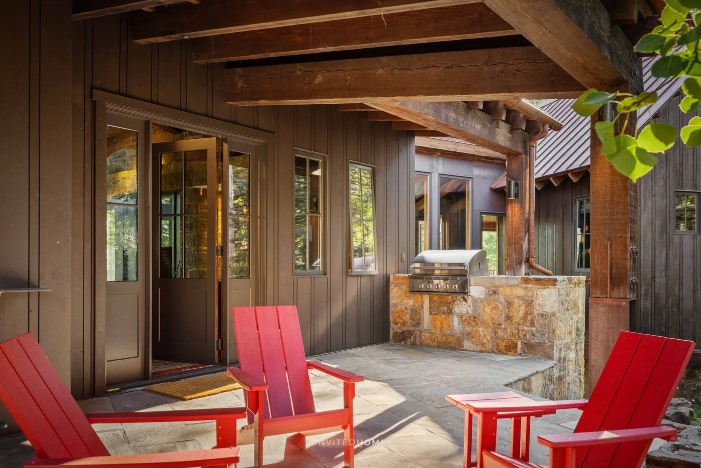 A covered outdoor patio with red seating beside a stone counter.