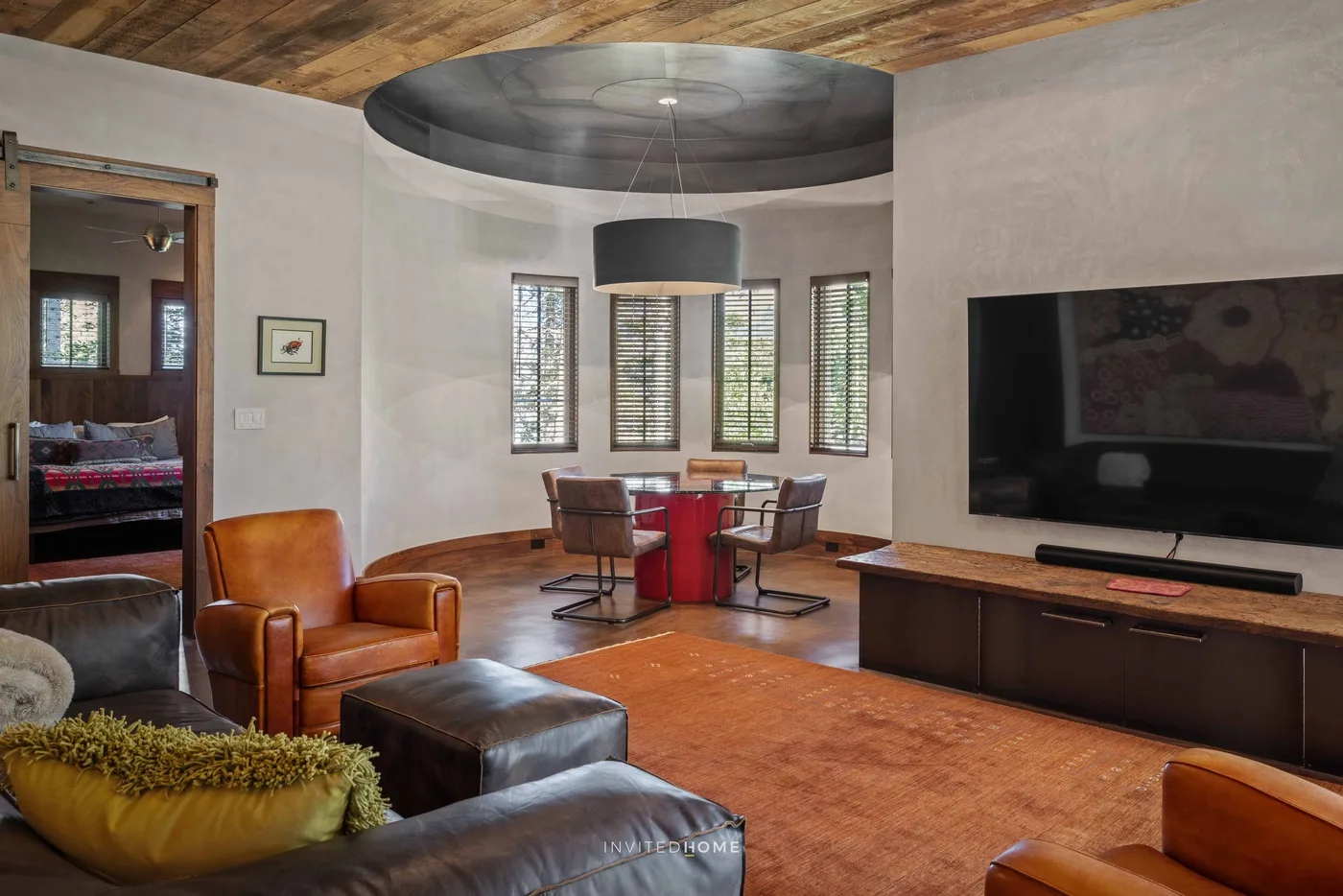 A living room with leather seating, a television, and a small dining table.