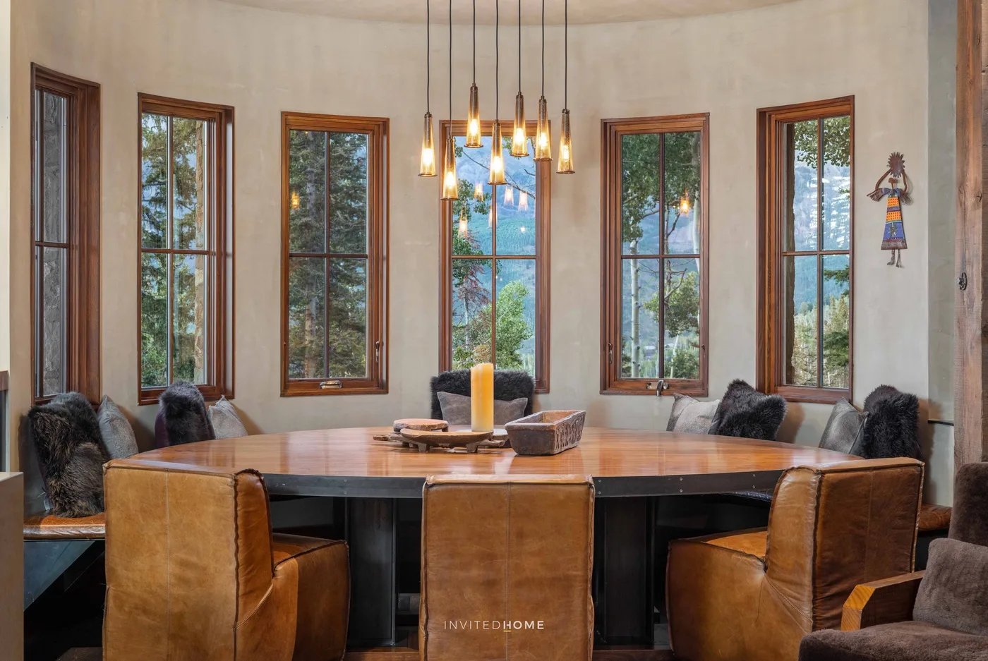 A dining area with a large wooden table and pendant lights.