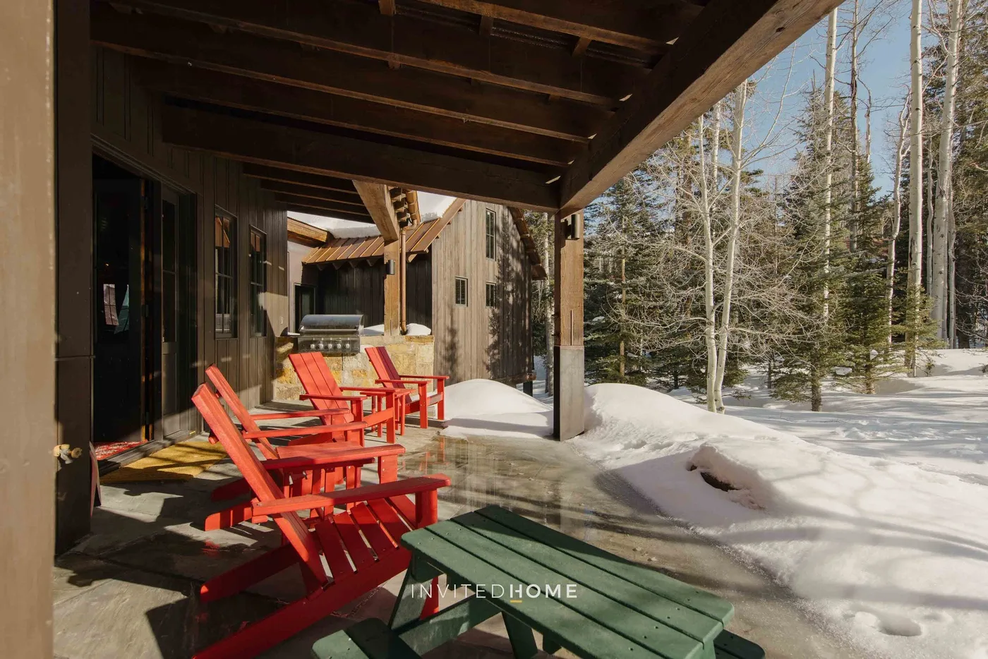 A covered outdoor patio with red seating and snow-covered ground beside it.