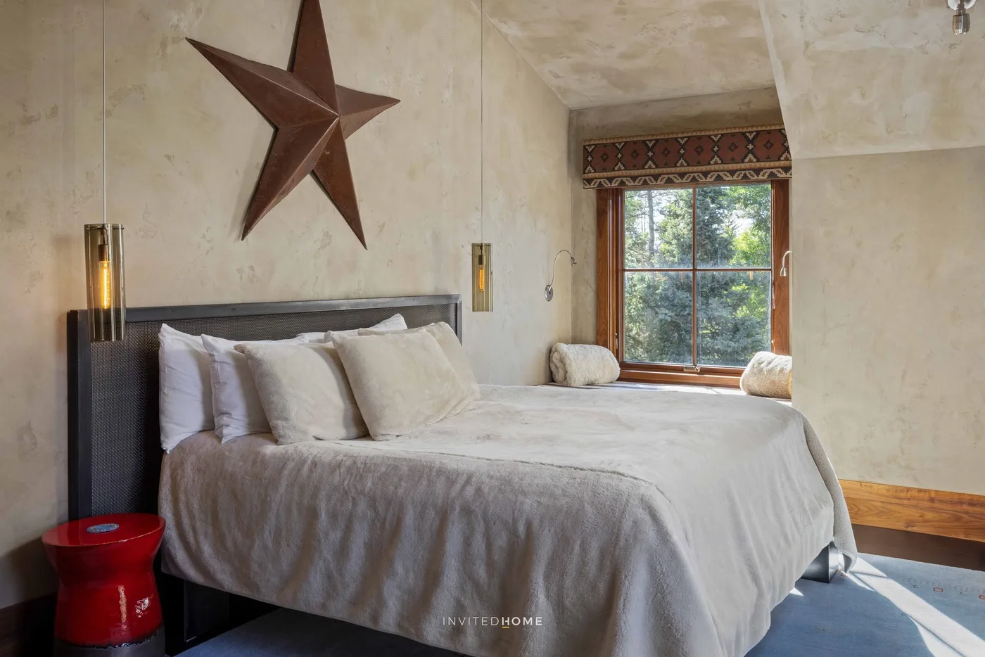 A bedroom with a bed beneath a large star-shaped wall decoration and a window.