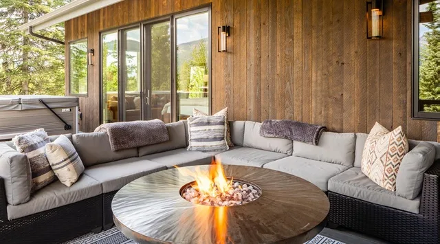 Una zona de estar al aire libre con asientos curvos alrededor de una mesa con fuego.