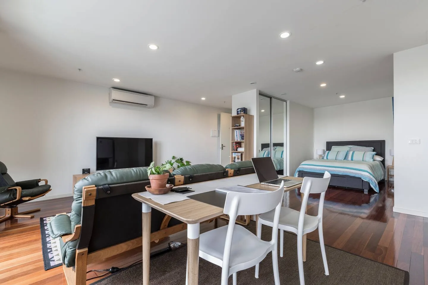 Una zona combinada de estar y dormitorio tiene una mesa de comedor y una cama.