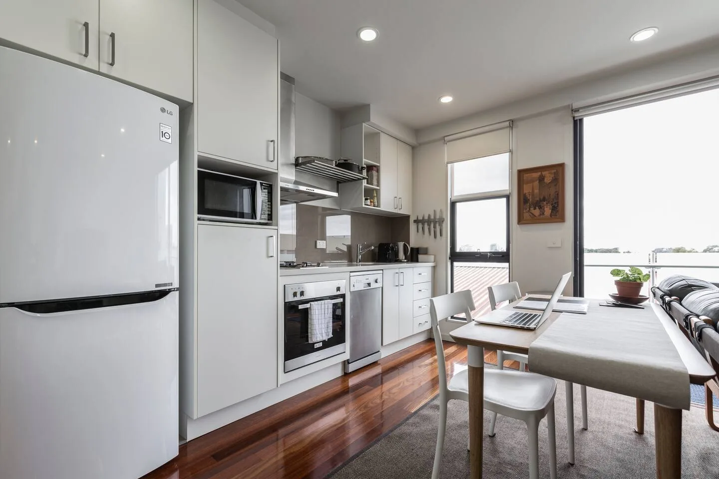 Una cocina y zona de comedor con una mesa junto a las ventanas.