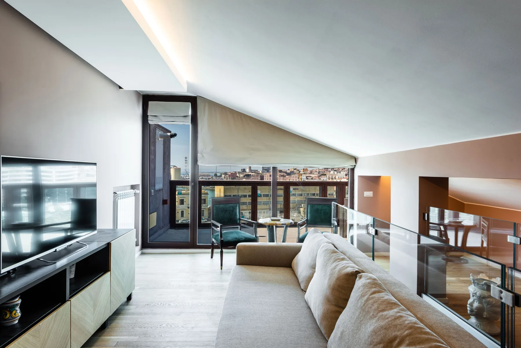 A bright loft living area with seating beside large windows overlooking the city.
