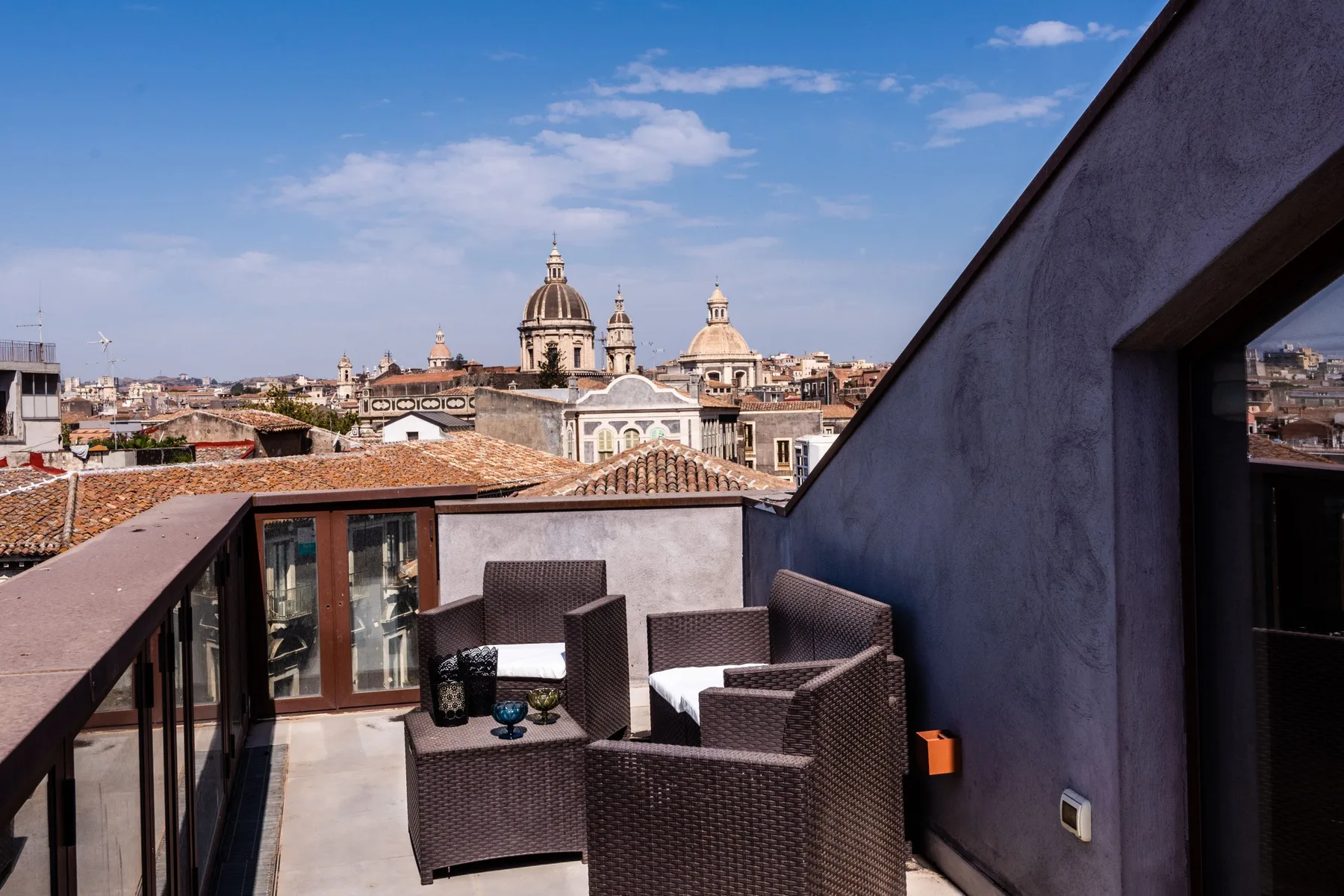 A rooftop terrace with outdoor seating overlooks a city skyline.