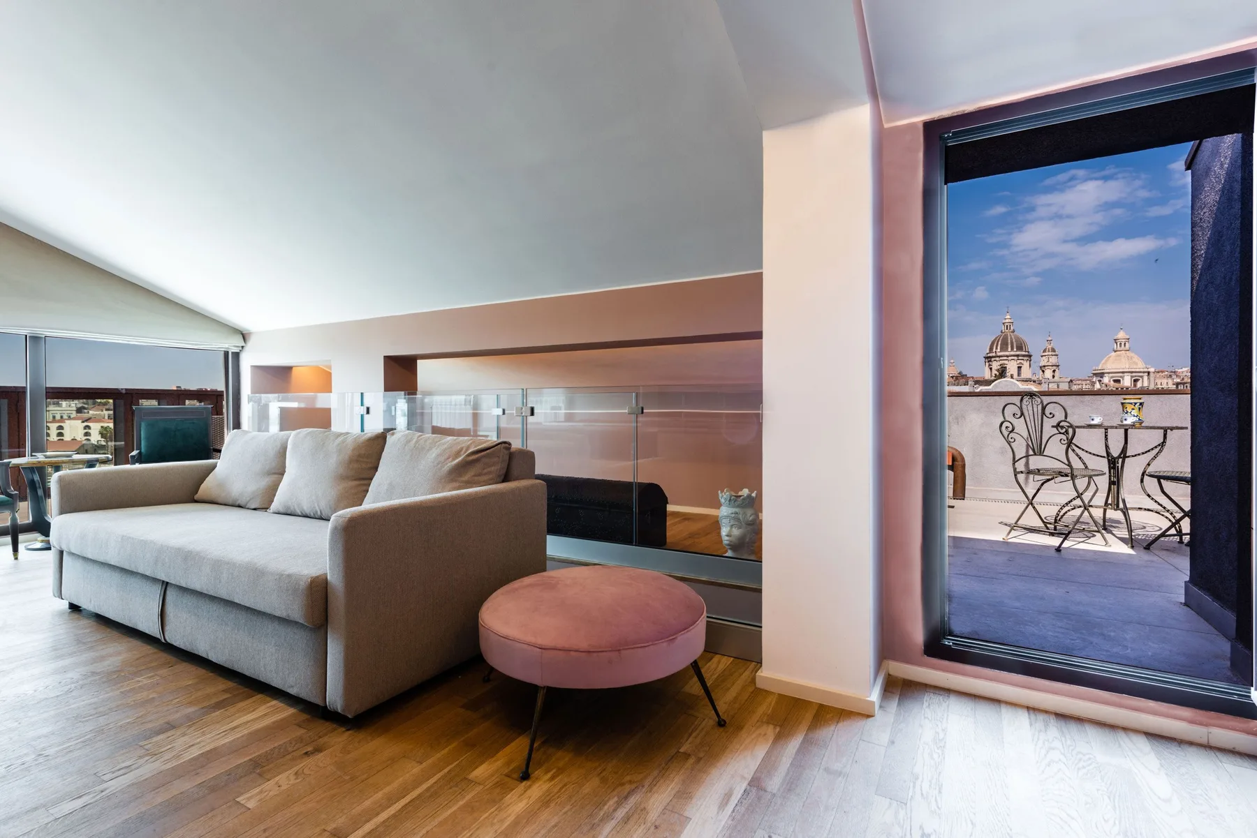 Una sala luminosa con un sofá y una puerta abierta hacia un balcón.