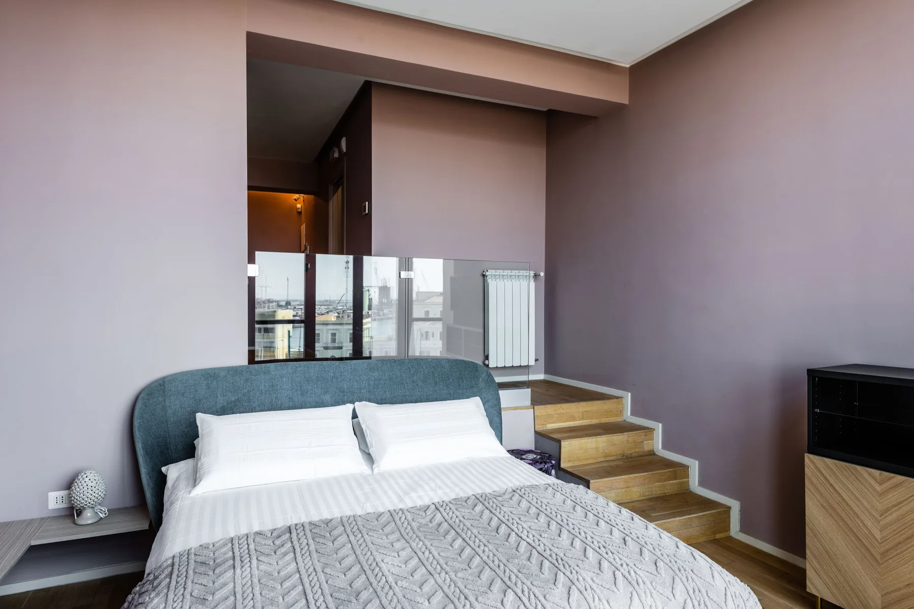 A bedroom with a neatly made bed and wooden steps beside it.
