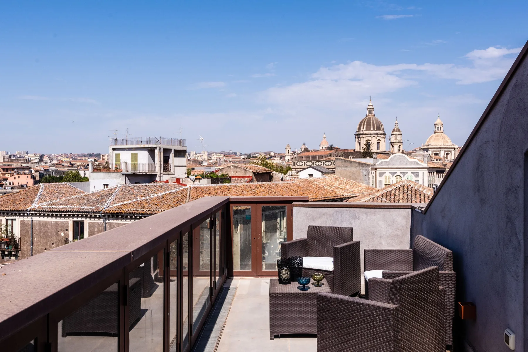 Una terraza en la azotea con asientos al aire libre da a tejados de tejas y cúpulas.
