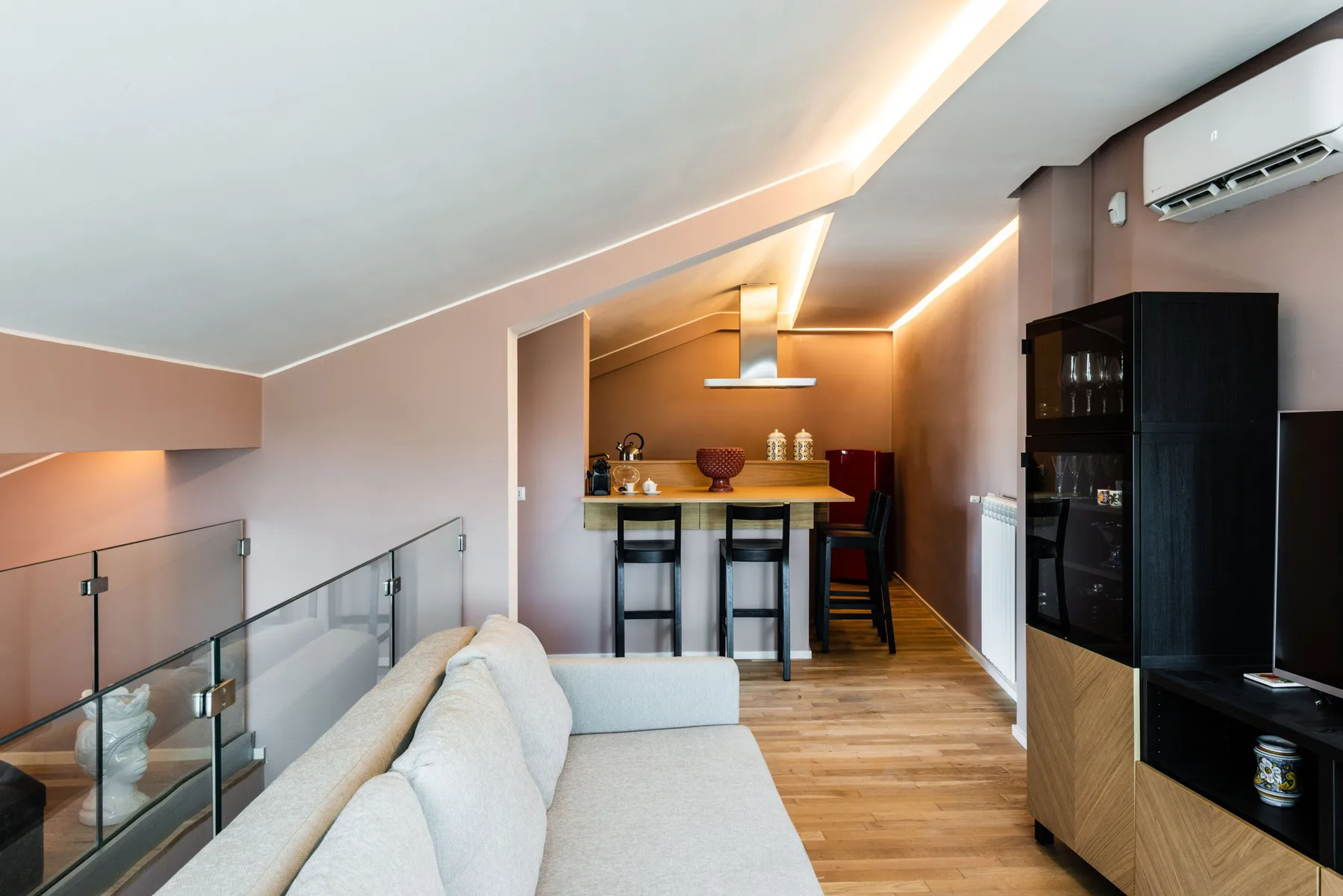A modern living area opens onto a compact kitchen with a breakfast counter.