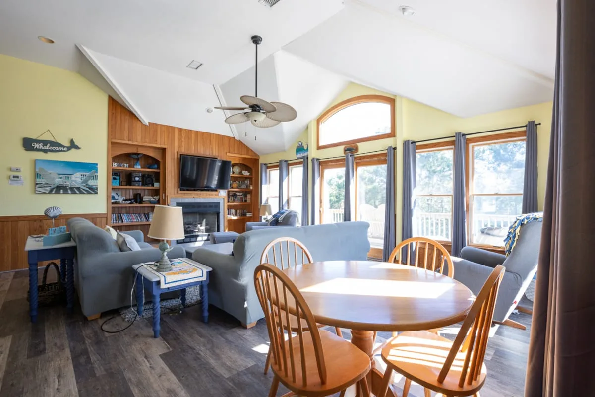 A bright living and dining area with seating around a wooden table.