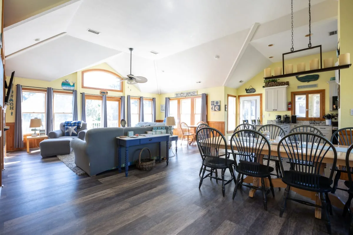 An open-plan living and dining area with seating, a dining table, and large windows.