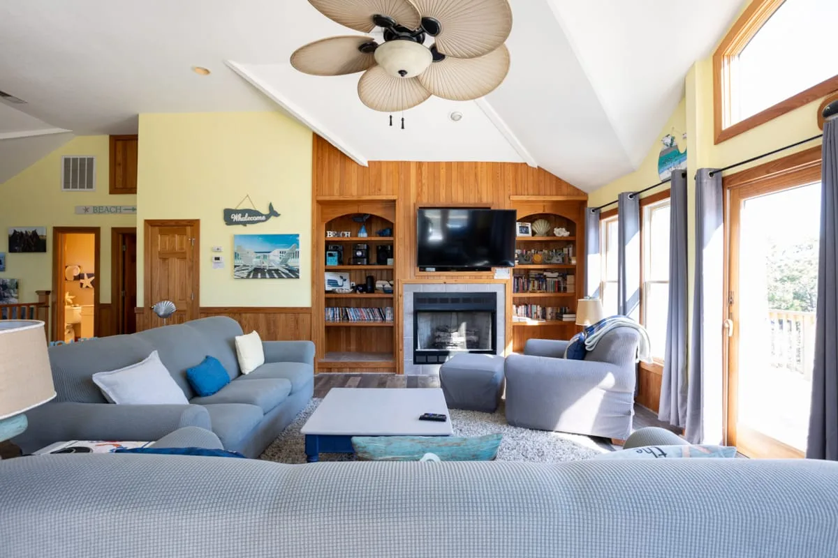 A living room with seating arranged around a fireplace and television.