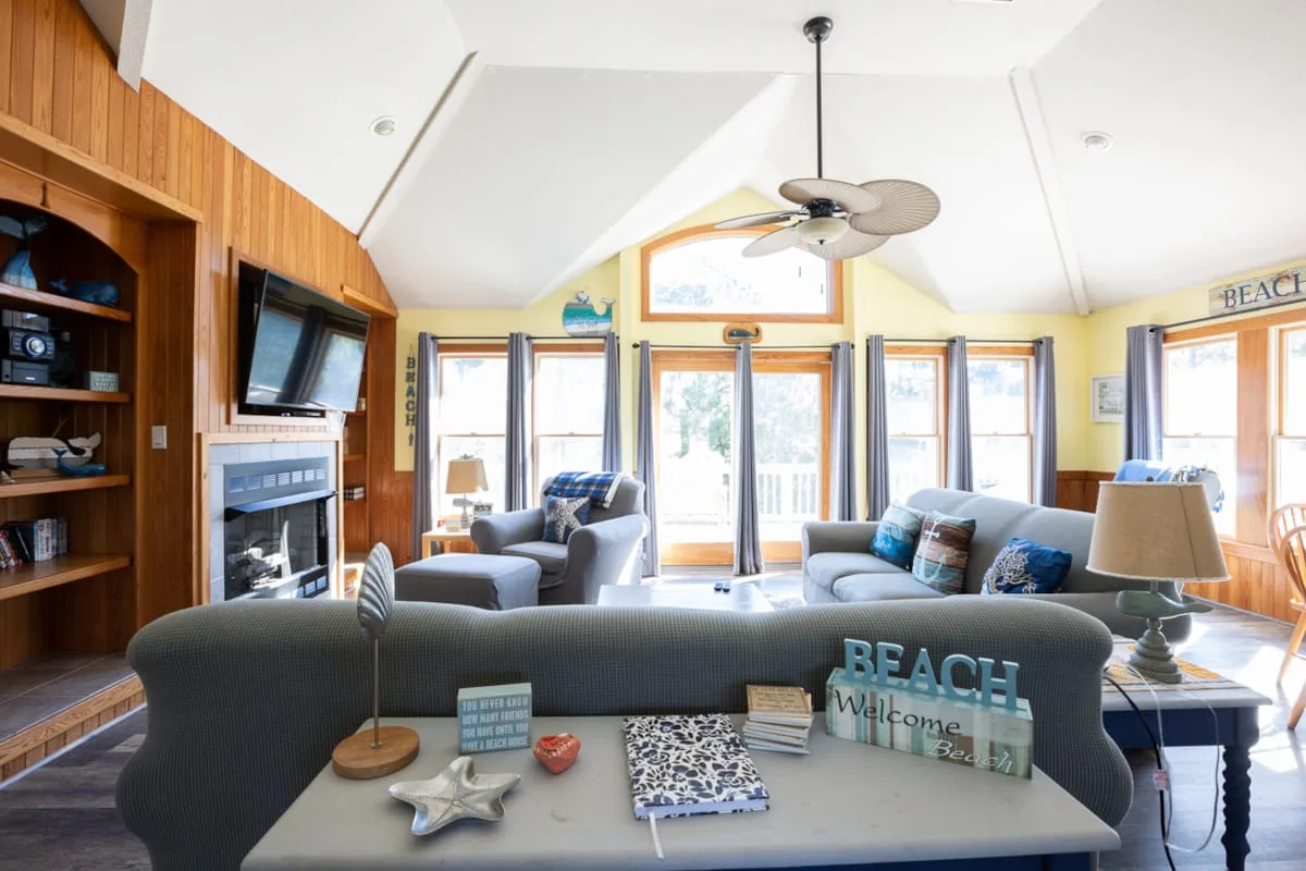 A bright living room with seating arranged around a low table and large windows.