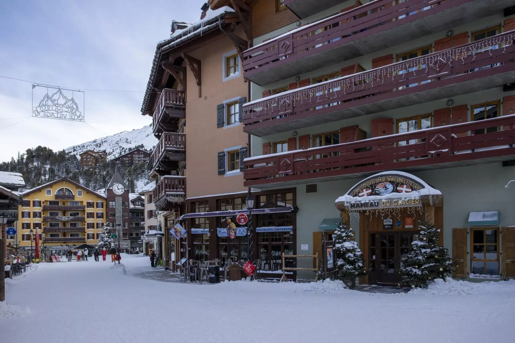 Calle peatonal cubierta de nieve junto a un edificio de varios pisos con balcones.