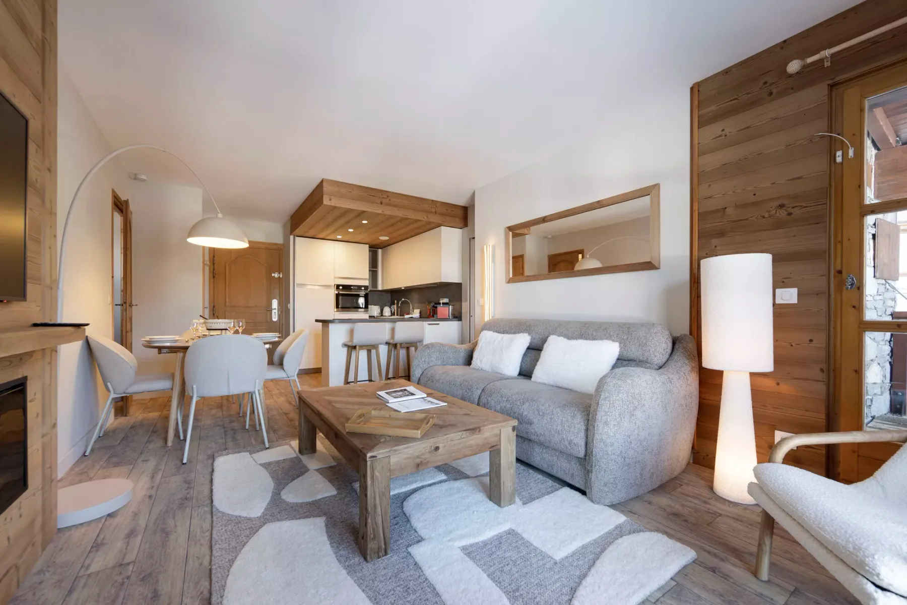 Sala de estar con sofá gris, mesa de centro y cocina abierta.