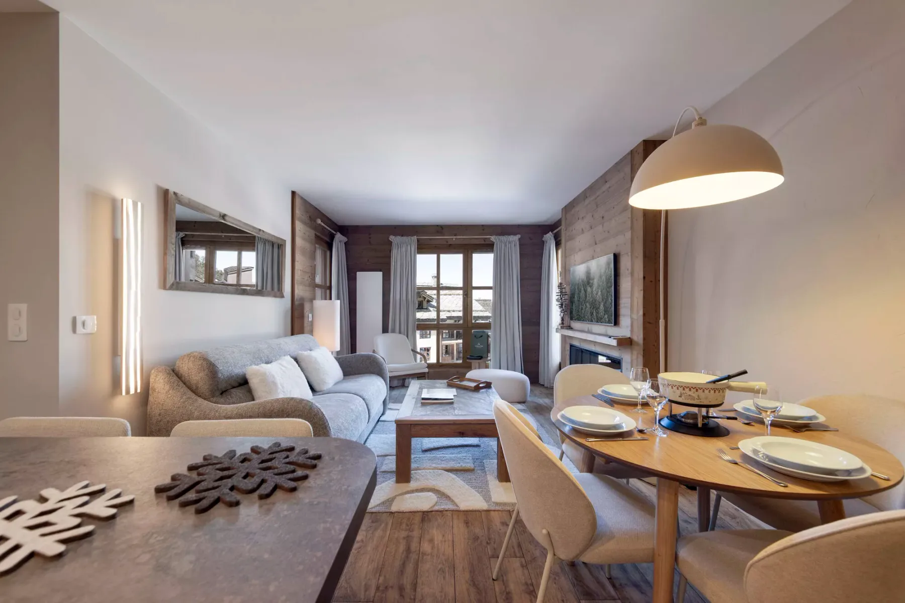 Una zona de estar y comedor con asientos, una mesa y ventanas grandes.