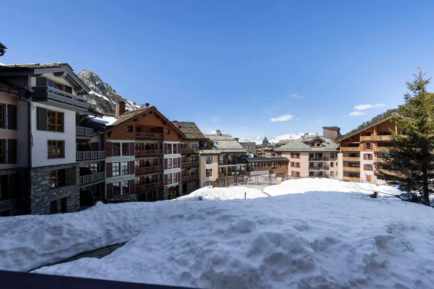Edificios de montaña cubiertos de nieve se alzan bajo un cielo azul despejado.