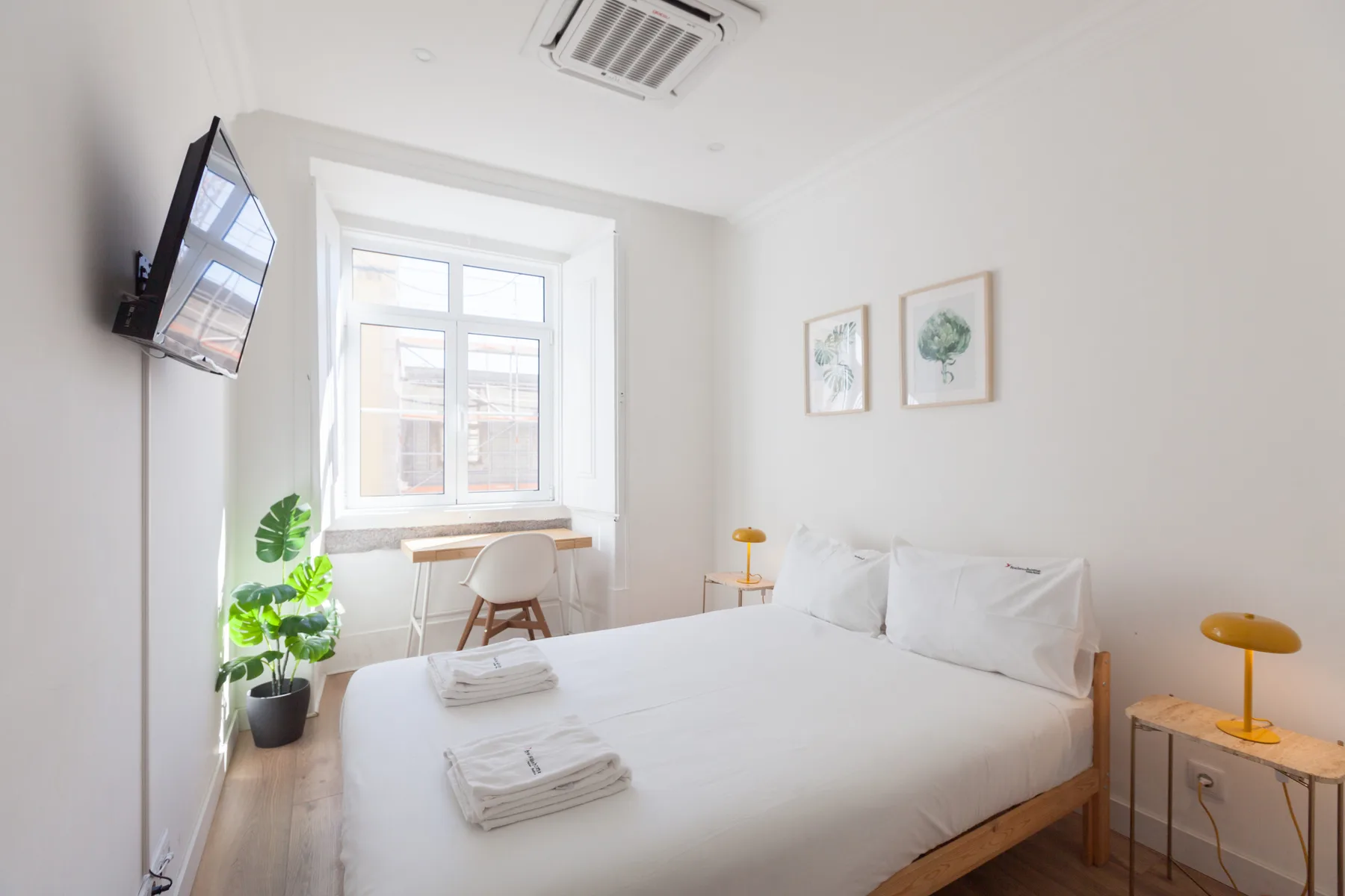 A bright bedroom with a bed, a window, and a small table.