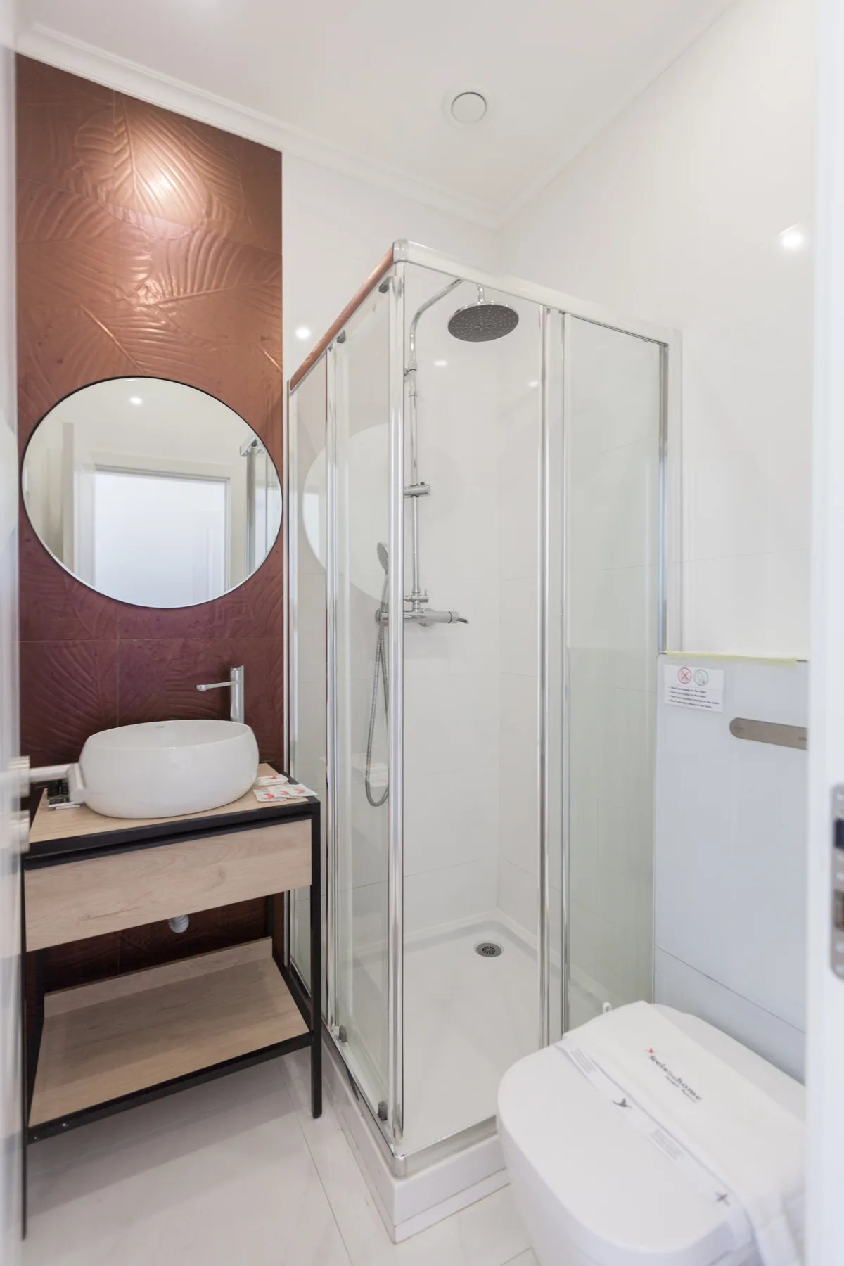 A bathroom with a glass shower, a vessel sink, and a toilet.