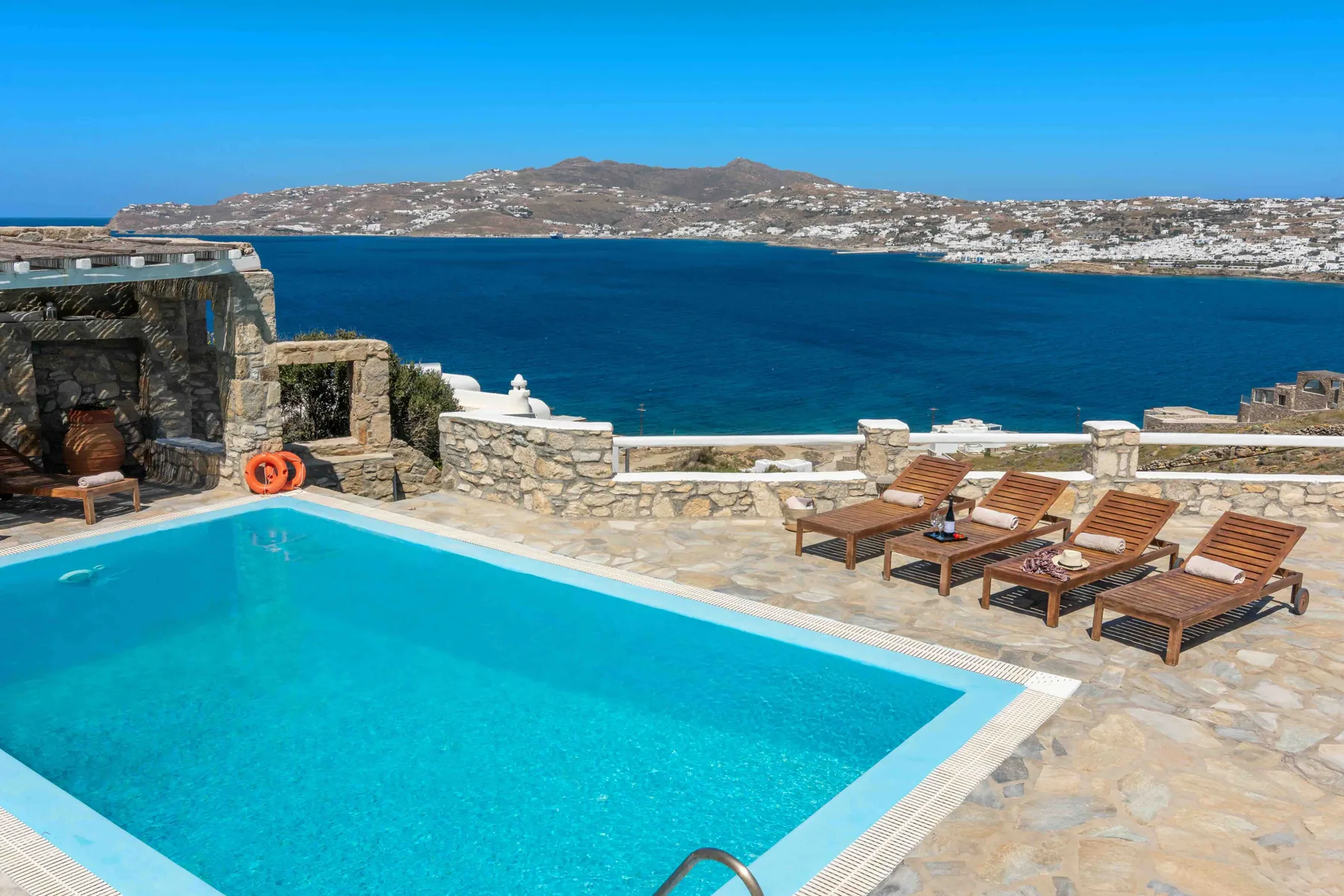A swimming pool and sun loungers overlook the sea from a stone terrace.