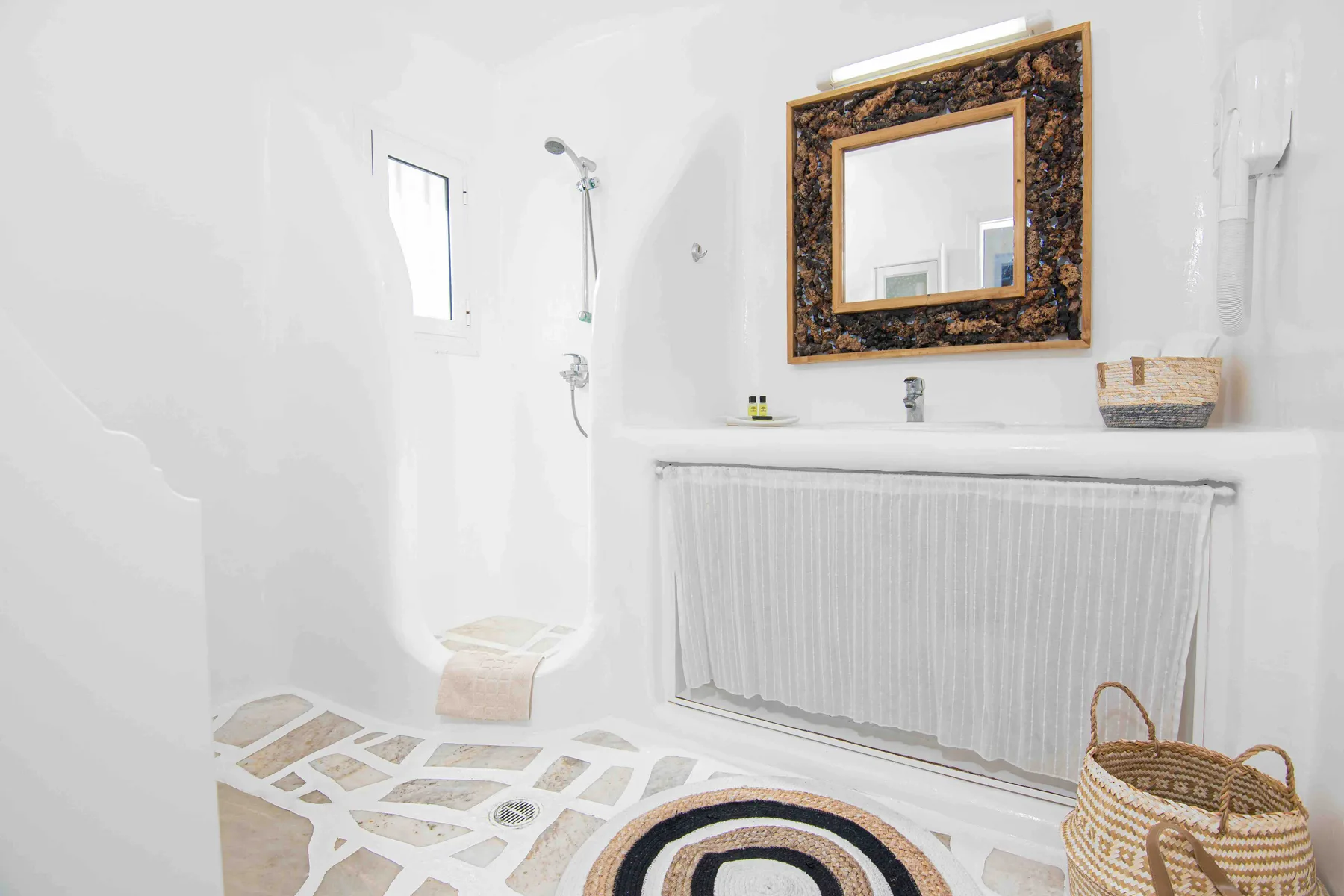 A bright bathroom with a shower, a sink, and a patterned floor.
